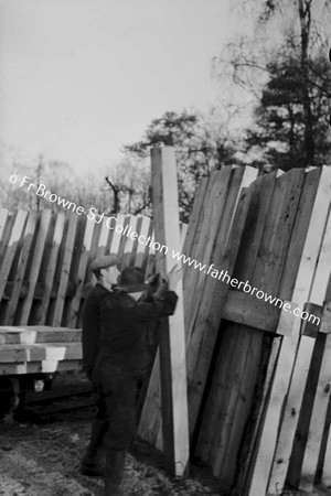 LUMBERING IN LEIX PILE OF WOOD WITH MEN IN FOREGROUND